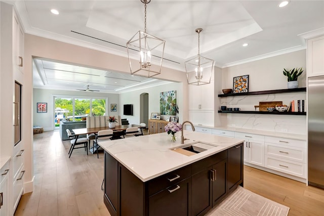 kitchen featuring white cabinets, light hardwood / wood-style flooring, sink, and decorative light fixtures