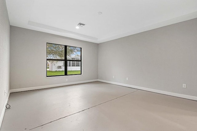 spare room featuring a tray ceiling and concrete flooring