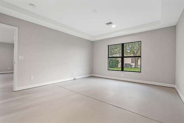 spare room featuring a raised ceiling and concrete floors