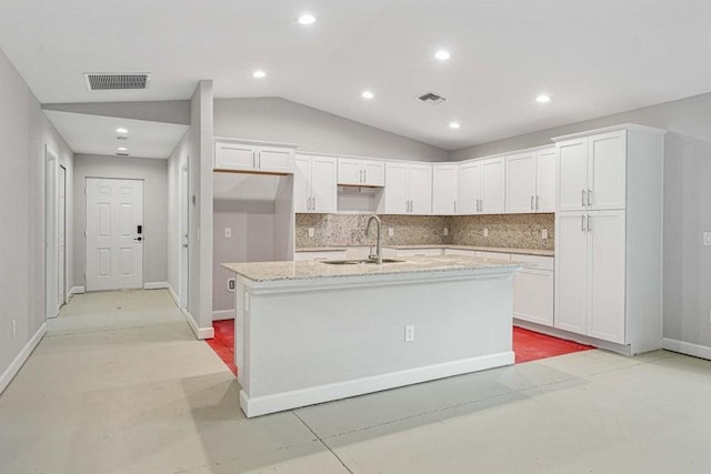 kitchen featuring white cabinetry, sink, tasteful backsplash, vaulted ceiling, and a center island with sink