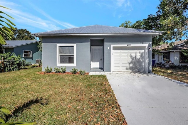 ranch-style home featuring metal roof, an attached garage, driveway, stucco siding, and a front yard