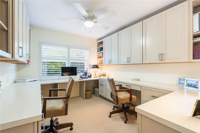 carpeted office featuring built in desk and ceiling fan