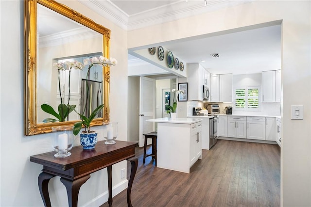 kitchen with white cabinetry, ornamental molding, appliances with stainless steel finishes, dark hardwood / wood-style flooring, and decorative backsplash