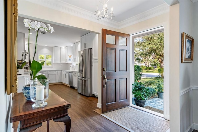 entrance foyer featuring an inviting chandelier, ornamental molding, sink, and dark wood-type flooring