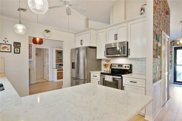 kitchen with white cabinets, stainless steel appliances, light stone counters, and ceiling fan