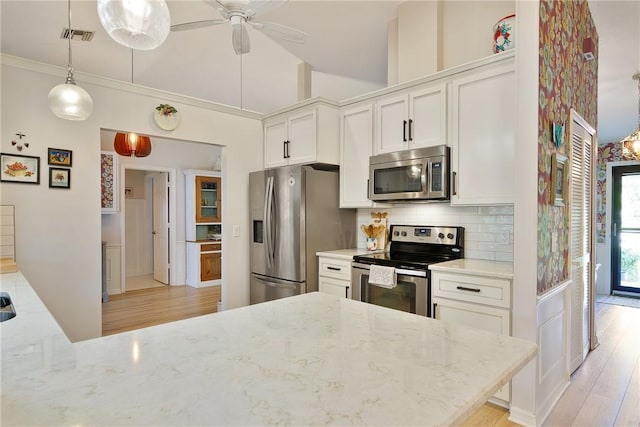 kitchen featuring ceiling fan, light stone countertops, white cabinets, and appliances with stainless steel finishes