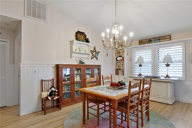 dining space with a notable chandelier, built in shelves, and light hardwood / wood-style flooring