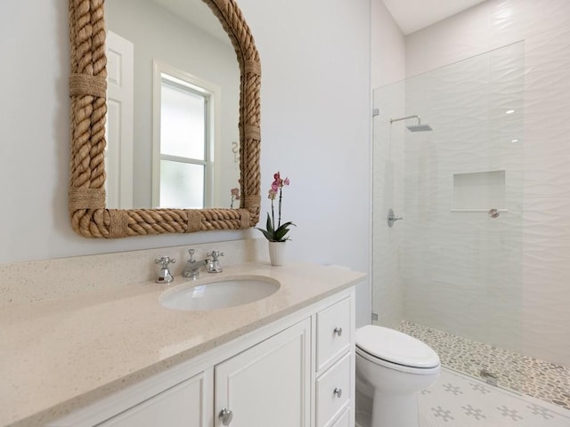 bathroom featuring vanity, toilet, and a tile shower