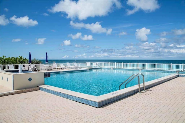 view of swimming pool with a water view and a patio area