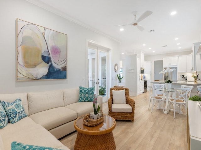 living room with crown molding, ceiling fan, and light hardwood / wood-style flooring