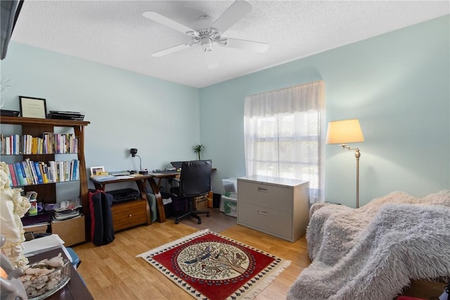 home office featuring a textured ceiling, light wood-style flooring, and ceiling fan