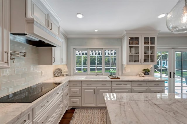 kitchen with black electric cooktop, a healthy amount of sunlight, sink, and white cabinets