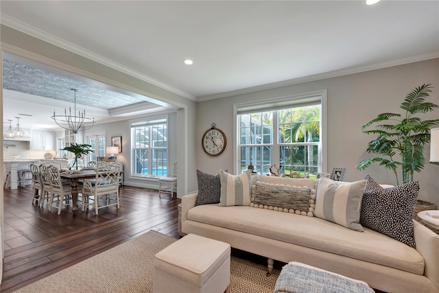 living room featuring crown molding, dark wood-type flooring, and an inviting chandelier