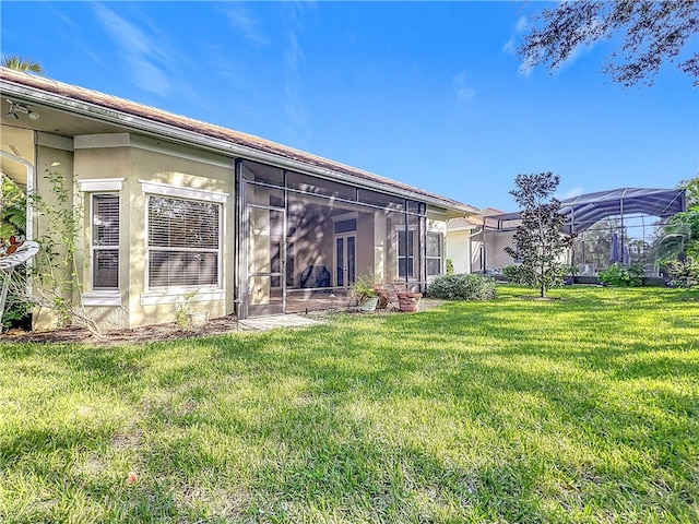 back of property with a yard and stucco siding