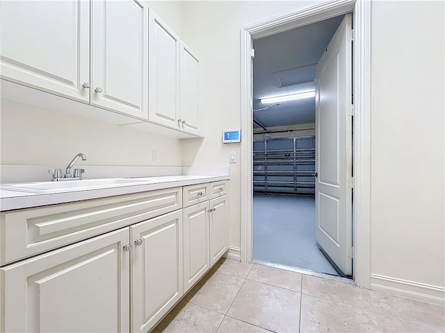 laundry area featuring light tile patterned floors, baseboards, and a sink