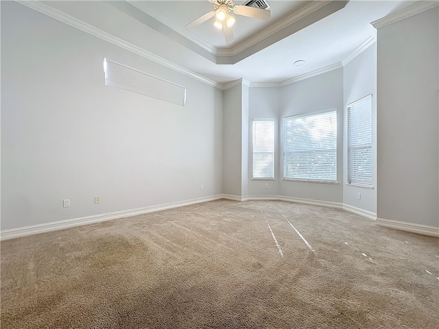 spare room with baseboards, a tray ceiling, light colored carpet, and crown molding