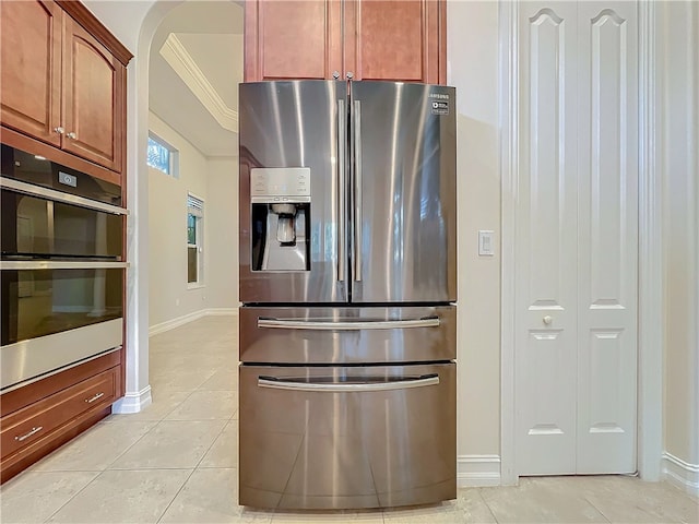 kitchen featuring baseboards, appliances with stainless steel finishes, arched walkways, and light tile patterned flooring