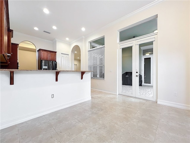 kitchen featuring stone countertops, visible vents, black fridge with ice dispenser, a kitchen breakfast bar, and crown molding