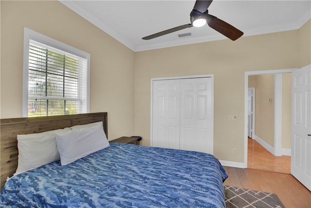 bedroom with ceiling fan, ornamental molding, a closet, and wood-type flooring