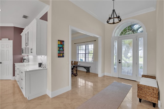 foyer featuring a wealth of natural light, an inviting chandelier, and crown molding