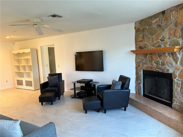 living room with a fireplace, a textured ceiling, and ceiling fan