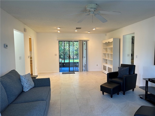 living room with ceiling fan, light tile patterned flooring, and a textured ceiling