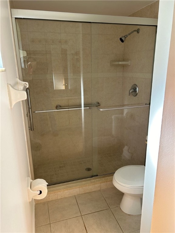 bathroom featuring tile patterned flooring, toilet, and an enclosed shower