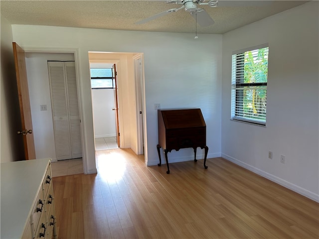 empty room with a textured ceiling, light hardwood / wood-style floors, and ceiling fan