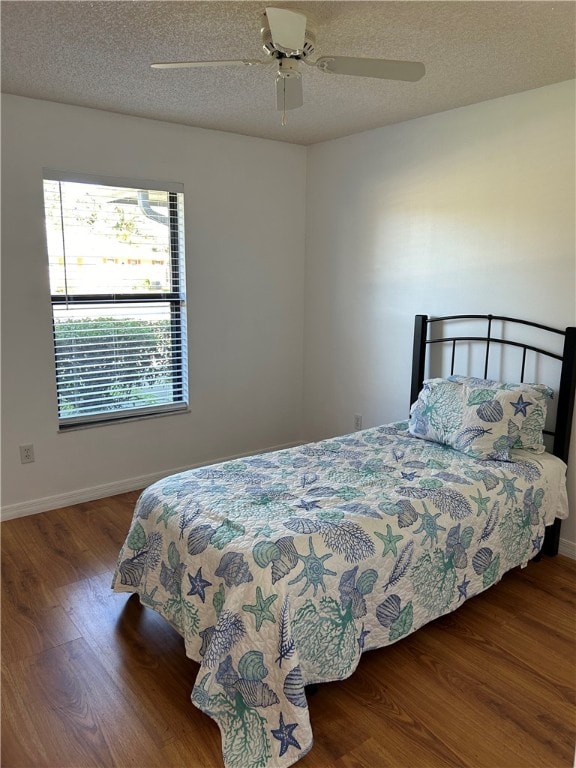 bedroom with ceiling fan, wood-type flooring, and a textured ceiling