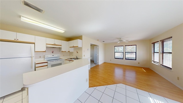 kitchen featuring tasteful backsplash, white cabinetry, sink, light wood-type flooring, and white appliances