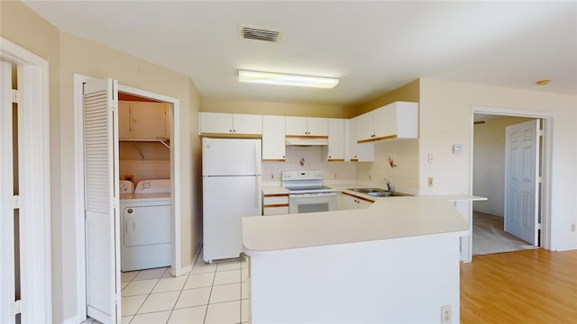 kitchen featuring tasteful backsplash, separate washer and dryer, sink, white cabinets, and white appliances