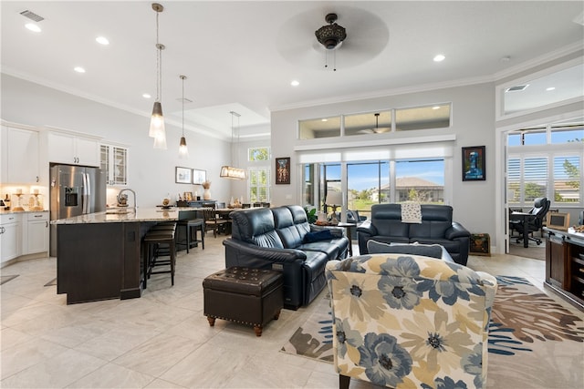 living room featuring ceiling fan, crown molding, sink, and light tile patterned floors