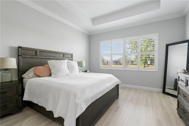 bedroom featuring crown molding, light hardwood / wood-style floors, and a raised ceiling