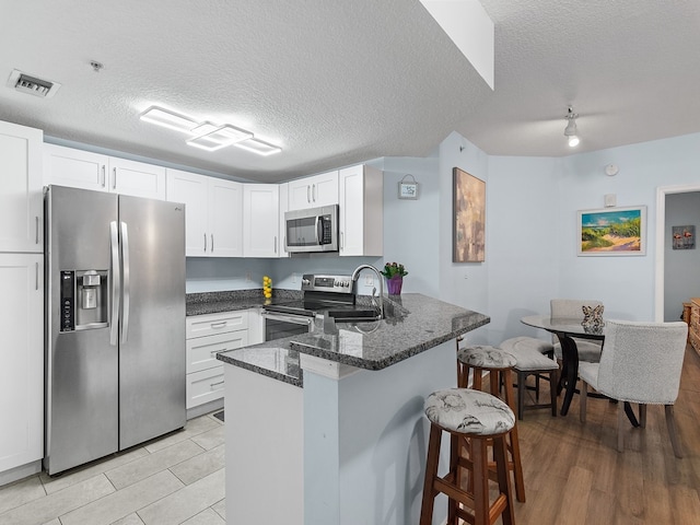 kitchen featuring white cabinets, a textured ceiling, and appliances with stainless steel finishes