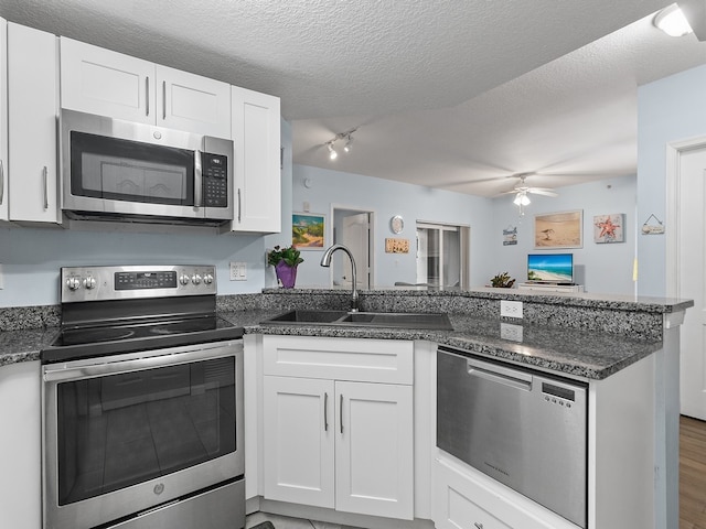 kitchen with sink, hardwood / wood-style flooring, appliances with stainless steel finishes, white cabinetry, and kitchen peninsula