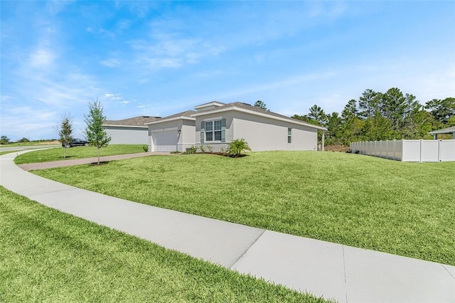 view of front of house featuring a front yard, fence, driveway, an attached garage, and stucco siding