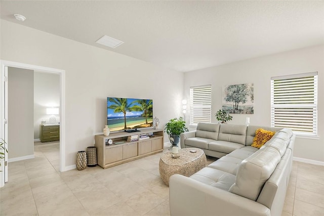 living area featuring light tile patterned floors, visible vents, baseboards, and a healthy amount of sunlight