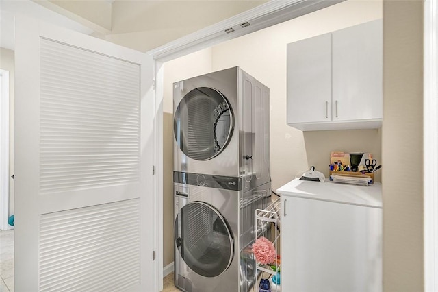 clothes washing area with cabinet space and stacked washer / drying machine