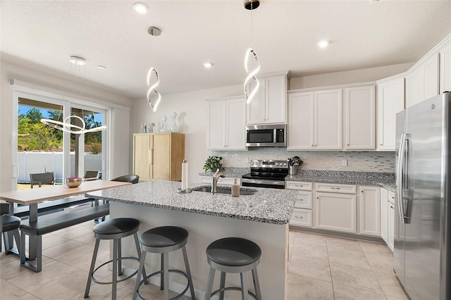 kitchen featuring a sink, white cabinetry, stainless steel appliances, decorative backsplash, and light stone countertops