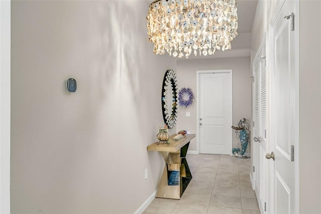 hallway with light tile patterned floors, baseboards, and an inviting chandelier