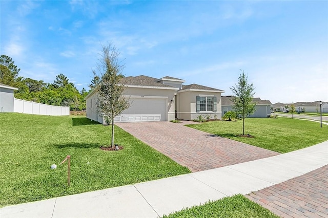 prairie-style house featuring stucco siding, a front lawn, decorative driveway, fence, and a garage