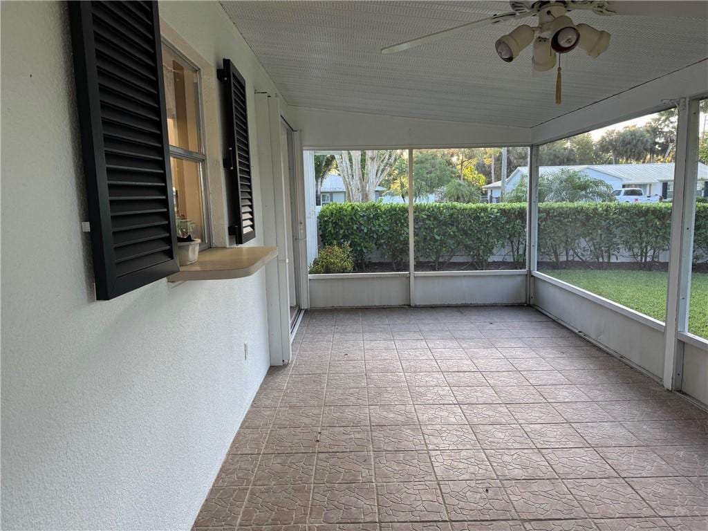 unfurnished sunroom featuring a ceiling fan and a healthy amount of sunlight