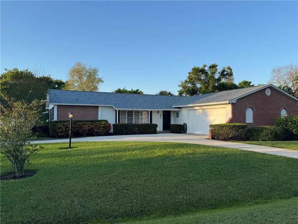 ranch-style home with brick siding, a garage, concrete driveway, and a front yard