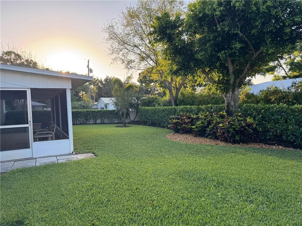 yard at dusk featuring a sunroom