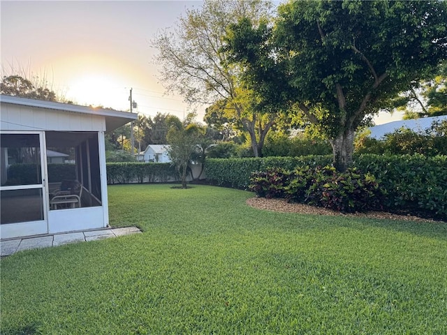 yard at dusk featuring a sunroom