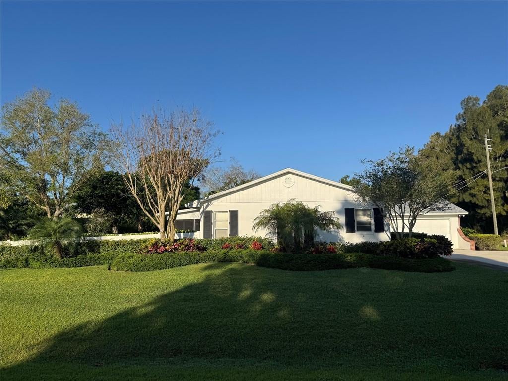 view of side of home featuring a lawn, an attached garage, and driveway