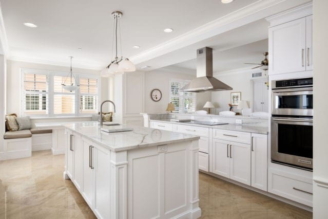 kitchen featuring a center island with sink, open floor plan, double oven, black electric stovetop, and extractor fan