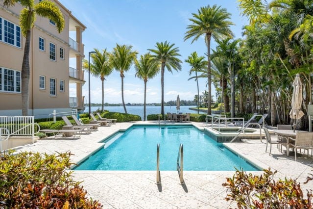 view of swimming pool featuring a water view, a pool with connected hot tub, and a patio area