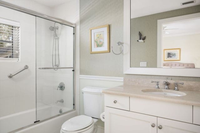 bathroom featuring visible vents, toilet, vanity, and shower / bath combination with glass door