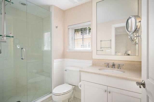 bathroom featuring vanity, a wainscoted wall, toilet, and a stall shower